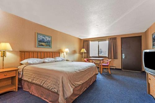 a hotel room with a large bed and a desk at Travelodge by Wyndham Pioneer Villa in Halsey