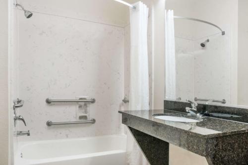 a bathroom with a sink and a bath tub at Super 8 by Wyndham Brookshire TX in Brookshire