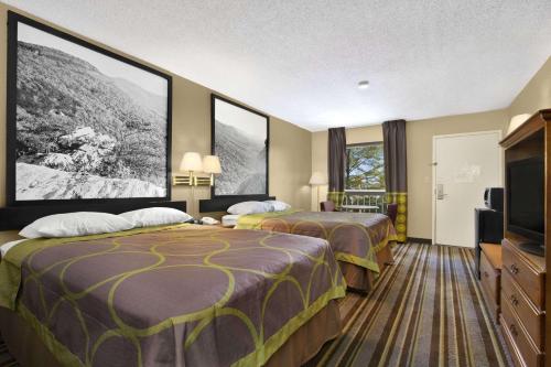 a hotel room with two beds and a flat screen tv at Super 8 by Wyndham Oxford in Oxford