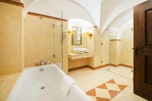 a bathroom with a tub and a sink and a mirror at Arcadia Boutique Hotel in Bratislava