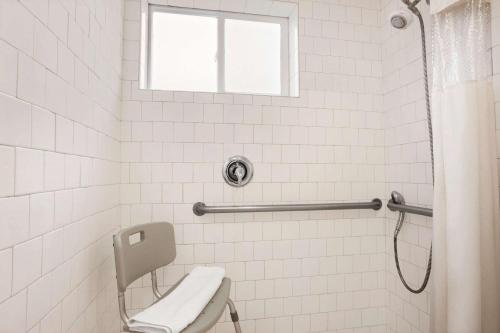 a white tiled bathroom with a toilet and a window at Travelodge by Wyndham Bakersfield in Bakersfield