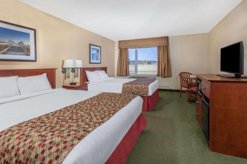 a hotel room with two beds and a flat screen tv at Super 8 by Wyndham Campbellton NB in Campbellton