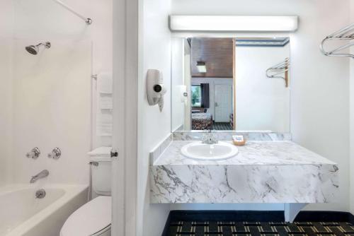 een witte badkamer met een marmeren wastafel en een bad bij Post Oak Inn in Brownwood