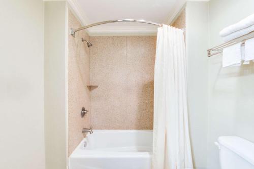 a bathroom with a tub and a white shower curtain at Knights Inn Van Horn in Van Horn