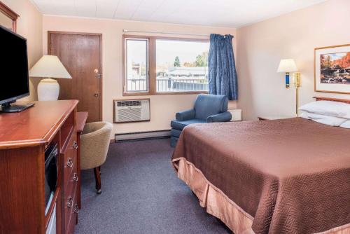a hotel room with a bed and a television at Travelodge by Wyndham Kalispell in Kalispell