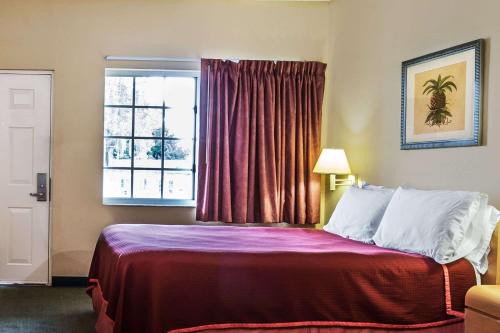 a hotel room with a bed with a window at Travelodge Suites by Wyndham Lake Okeechobee in Okeechobee