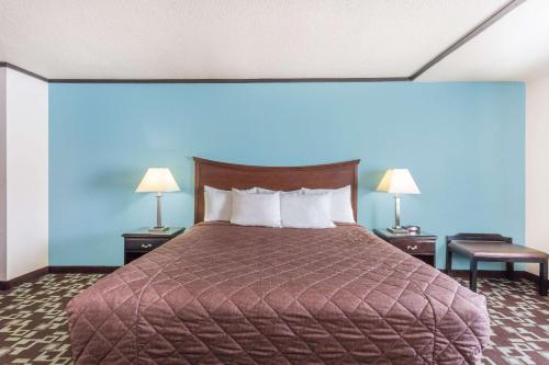 a bedroom with a bed with a blue wall and two lamps at Super 8 by Wyndham Daleville/Roanoke in Daleville