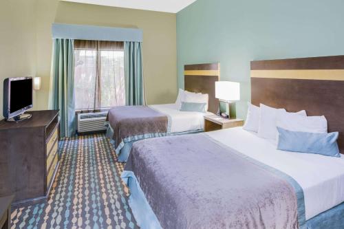 a hotel room with two beds and a television at Wingate by Wyndham Bossier City in Bossier City
