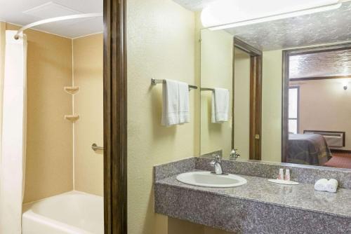 a bathroom with a sink and a tub and a mirror at Super 8 by Wyndham Enid in Enid