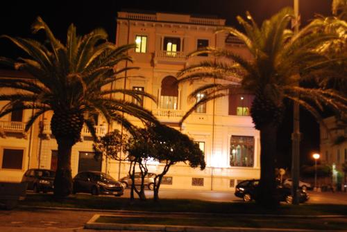 two palm trees in front of a building at night at Villa Tina Hotel in Viareggio