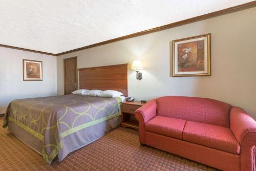 a hotel room with a bed and a couch at Super 8 by Wyndham Enid in Enid