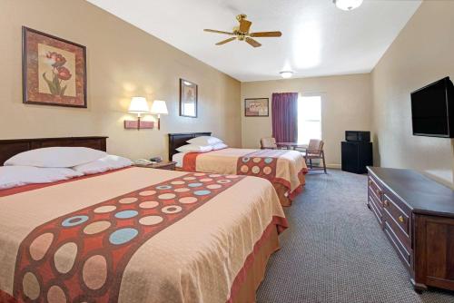 a hotel room with two beds and a flat screen tv at Super 8 by Wyndham St. Louis Airport in Woodson Terrace
