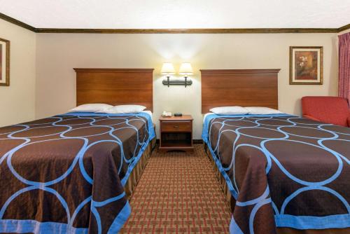 a hotel room with two beds and a chair at Super 8 by Wyndham Enid in Enid