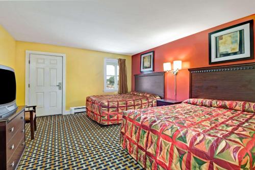 a hotel room with two beds and a flat screen tv at Budget Inn in South Portland