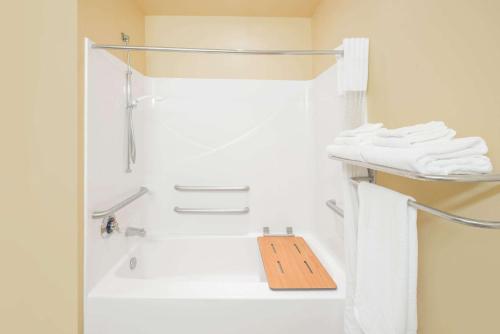La salle de bains est pourvue d'une douche et d'un panneau en bois sur une étagère. dans l'établissement Microtel Inn & Suites Quincy by Wyndham, à Quincy