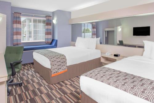 a hotel room with two beds and a tv at Microtel Inn and Suites by Wyndham Appleton in Appleton