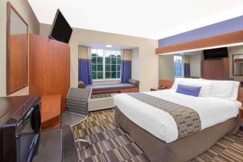 a hotel room with a bed and a flat screen tv at Microtel Inn and Suites Manistee in Manistee