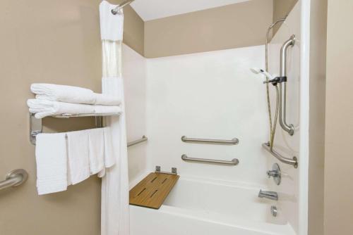 a bathroom with a bath tub and towels at Microtel Inn & Suites by Wyndham Hazelton/Bruceton Mills in Hazelton