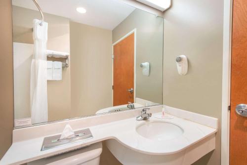 a bathroom with a sink and a mirror at Microtel Inn & Suites by Wyndham Hazelton/Bruceton Mills in Hazelton