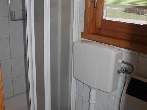 a white toilet in a bathroom with a window at Pretty Bungalow in Neubukow with Garden, Roof Terrace, BBQ in Neubukow