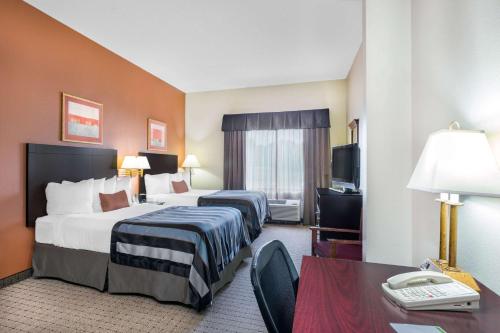 A bed or beds in a room at Wingate by Wyndham West Monroe