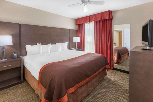 a hotel room with a large bed and a television at Affordable Suites of America Detroit-Warren in Warren