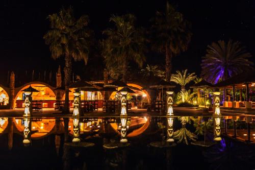 a pool at night with palm trees and umbrellas at Africa Jade Thalasso in Korba