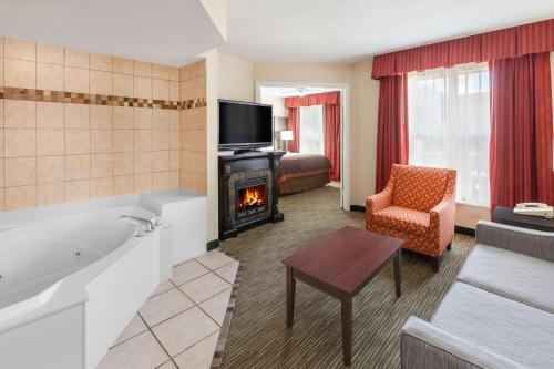 a living room with a tub and a fireplace at Affordable Suites of America Detroit-Warren in Warren