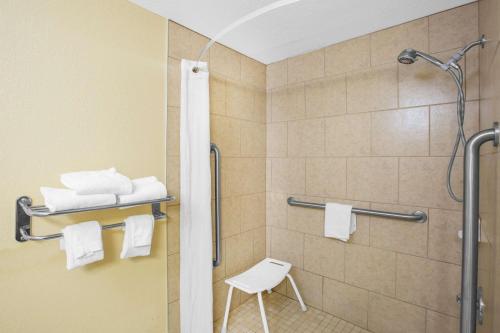 a shower with a white stool in a bathroom at Super 8 by Wyndham Clive IA in Clive