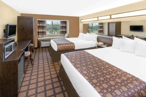 a hotel room with two beds and a television at Microtel Inn & Suites by Wyndham Ozark in Ozark