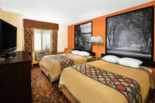 a hotel room with two beds and a flat screen tv at Super 8 by Wyndham Clive IA in Clive