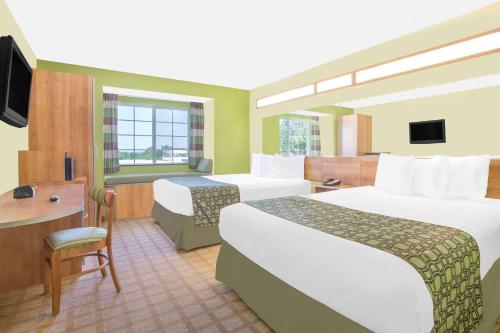 TuscumbiaにあるMicrotel Inn & Suites by Wyndham Tuscumbia/Muscle Shoalsのベッド2台とデスクが備わるホテルルームです。