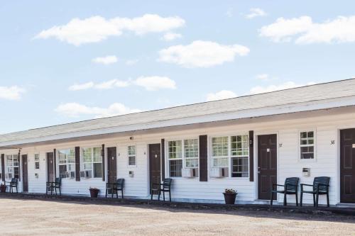 a white building with black chairs and windows at Lincoln Inn Fredericton in Fredericton