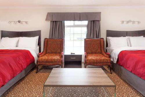 um quarto de hotel com duas camas e duas cadeiras em Knights Inn Kingston em Kingston