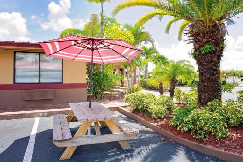 a picnic table with an umbrella next to a building at Knights Inn Port Charlotte in Port Charlotte