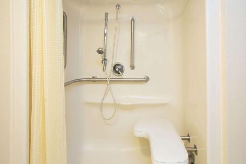 a bathroom with a toilet and a shower curtain at Travelodge by Wyndham Fort Myers Airport in Fort Myers
