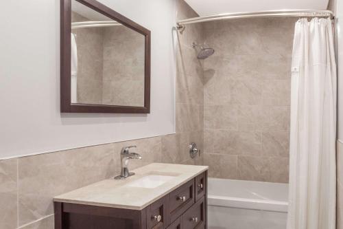 a bathroom with a sink and a shower with a mirror at Knights Inn Kingston in Kingston