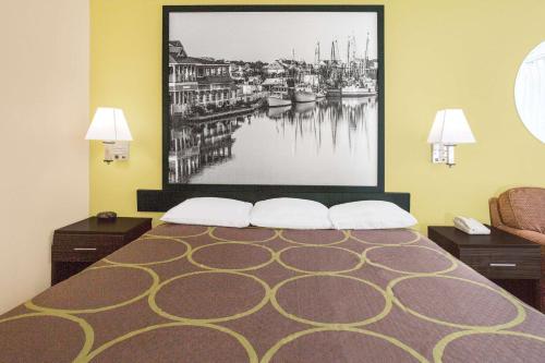 a hotel room with a bed with a large picture on the wall at Super 8 by Wyndham Sumter in Sumter