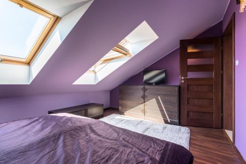 a purple bedroom with a bed and a tv at Apartament Osiedle Bałtyk in Grzybowo