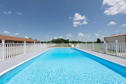 uma piscina com cerca branca e água azul em Knights Inn - Chanute em Chanute