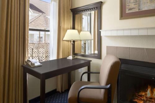 a hotel room with a desk and a fireplace at Hawthorn Extended Stay by Wyndham Fort Wayne in Fort Wayne