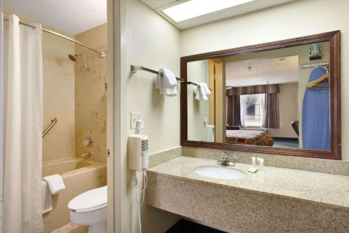 a bathroom with a sink and a toilet and a mirror at Super 8 by Wyndham New Iberia in New Iberia