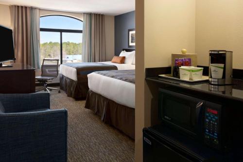 a hotel room with two beds and a television at Wingate Slidell New Orleans in Slidell