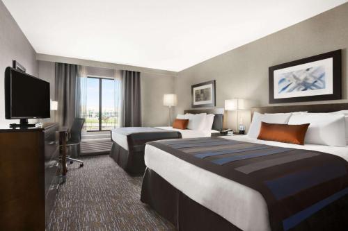 a hotel room with two beds and a flat screen tv at Wingate by Wyndham - Bismarck in Bismarck
