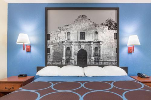 a bedroom with a painting of a building at Super 8 by Wyndham San Antonio at I-10 in San Antonio