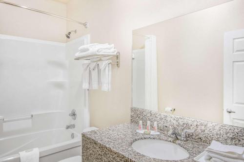 La salle de bains est pourvue d'un lavabo, d'une baignoire et d'un miroir. dans l'établissement High Point Inn & Suites Peace River, à Peace River