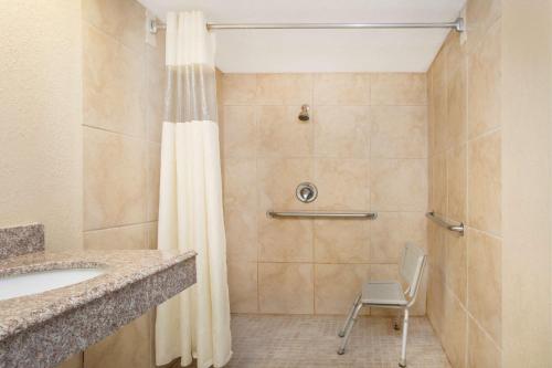 a bathroom with a shower with a sink and a chair at Super 8 by Wyndham San Antonio at I-10 in San Antonio