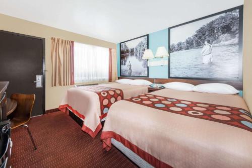 a hotel room with two beds and a large screen at Super 8 by Wyndham Midwest City OK in Midwest City
