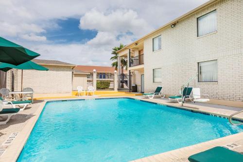 a swimming pool with chairs and a building at Super 8 by Wyndham San Antonio at I-10 in San Antonio
