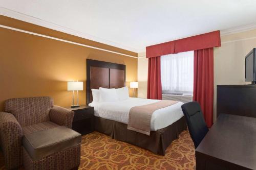 a hotel room with a bed and a chair at Travelodge by Wyndham Meadow Lake in Meadow Lake